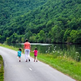 2 women walking on gray concrete road near green trees during daytime