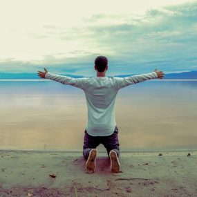 man wearing gray long-sleeved shirt beside seashore during daytime